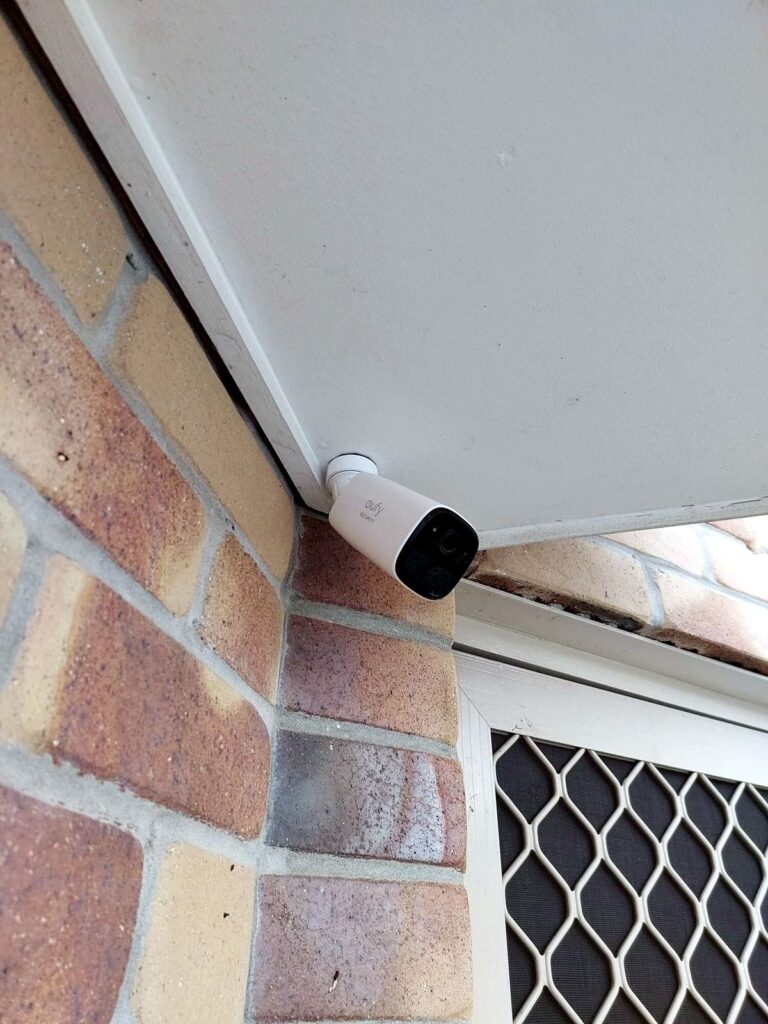 Outdoor wireless security camera installed beneath eave